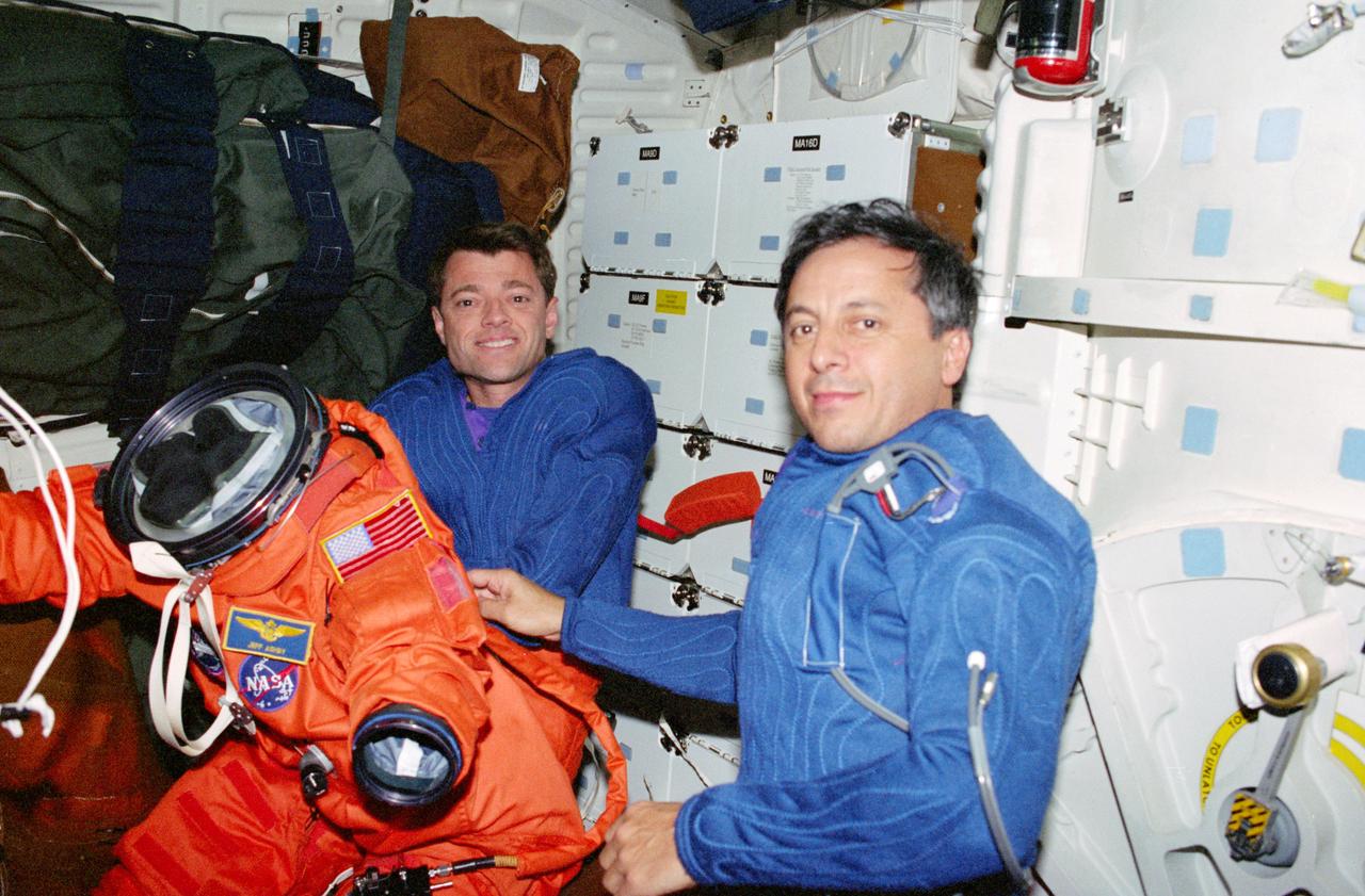 STS093-325-019 (22-27 July 1999) --- Astronauts Jeffrey S. Ashby (left), pilot, and Michel Tognini, mission specialist, prepare to put on Launch and Entry suits (LES) on the mid deck of the Earth-orbiting Space Shuttle Columbia. Tognini represents France&#0146;s Centre National d&#0146;Etudes Spatiales (CNES).