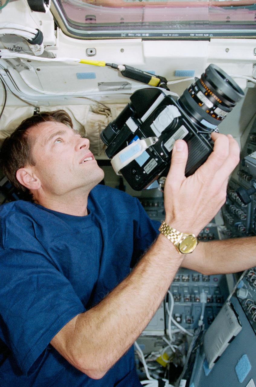 STS093-327-016 (23-27 July 1999) --- Astronaut Jeffrey S. Ashby, pilot, prepares to take a still photograph from Columbia's flight deck. Ashby and four other astronauts spent almost five days in Earth orbit in July 1999.