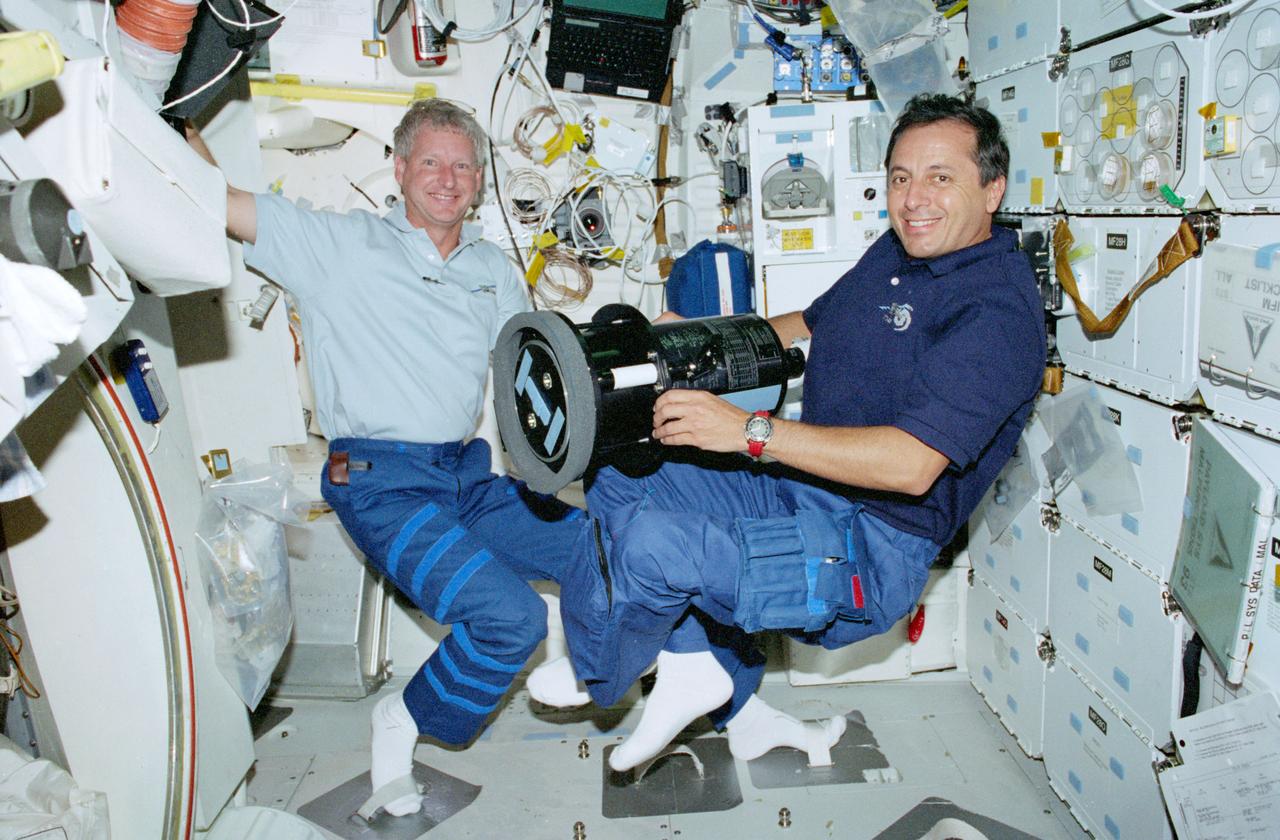 STS093-347-027 (23-27 July 1999) ---  Astronauts Steven A. Hawley (left) and  Michel Tognini, mission specialists, are pictured with the Southwest Ultraviolet Imaging System (SWUIS) on the middeck of the Space Shuttle Columbia.  SWUIS was  used during the mission to image planets and other solar system bodies in order to explore their atmospheres and surfaces in ultraviolet (UV) region of the spectrum, which astronomers value for diagnostic work. Tognini represents the Centre National d'Etudes Spatiales  (CNES) of France.