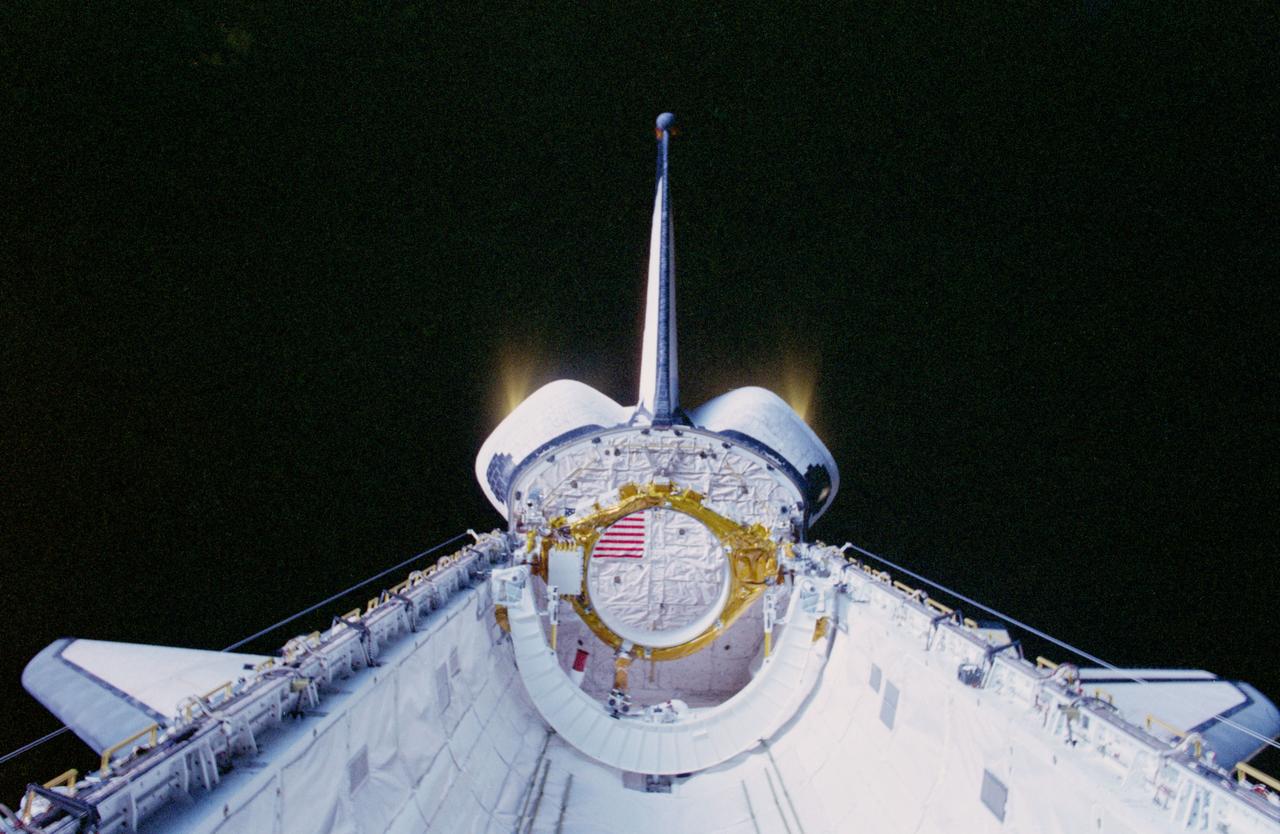 STS093-347-031 (22-27 July 1999) --- Black space forms the backdrop for this scene of the Orbital Maneuvering System (OMS) engine pods during a thruster burn photographed by one of the astronauts on the aft flight deck of the Space Shuttle Columbia.