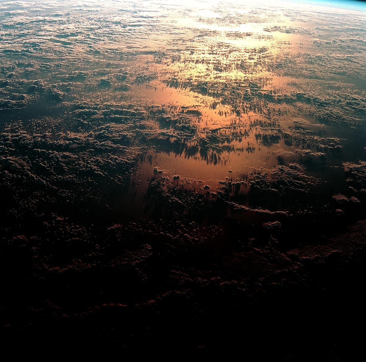 STS093-708-037 (23-27 July 1999) --- Sunset paints the ocean and low clouds with brilliant color and shadow just off the eastern coast of Brazil in the western South Atlantic in this photo from the Space Shuttle Columbia's 35th orbit.  Since one orbit of the shuttle around the Earth only takes 90 minutes, every 45 minutes the astronauts can witness a sunrise or sunset.  The shuttle was flying at a point located over 1.4 degrees north latitude and 26.9 west longitude.