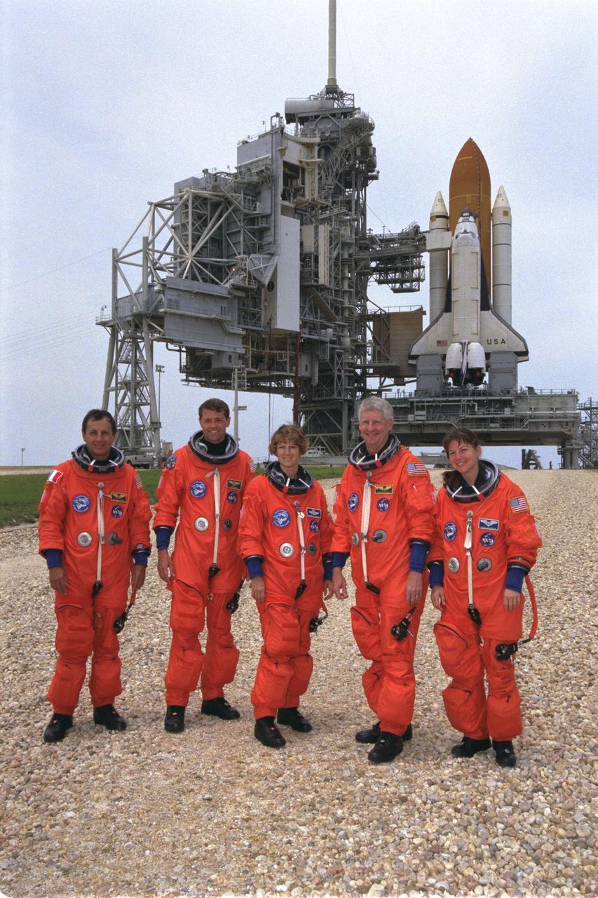 STS093-S-012 (24 June 1999) --- With the Space Shuttle Columbia sitting on Launch Pad 39B in the background, the STS-93 crew members pose for a photo during a break in training at the Kennedy Space Center (KSC). From the left are astronauts Michel Tognini, Jeffrey S. Ashby, Eileen M. Collins, Steven A. Hawley and Catherine G. Coleman. Tognini represents the European Space Agency (ESA). Collins will be the first woman to serve as a shuttle commander. The crew members have been taking part in a Terminal Countdown Demonstration Test, which familiarizes the astronauts with the mission, provides training in emergency egress from the orbiter and the launch pad, and includes the dress rehearsal culminating with a simulated main engine cut-off (MECO). The primary mission of this crew is the release of the Chandra X-ray Observatory, which is expected to allow scientists from around the world to obtain unprecedented X-ray images of the exotic environments in space to help understand the structure and evolution of the universe.