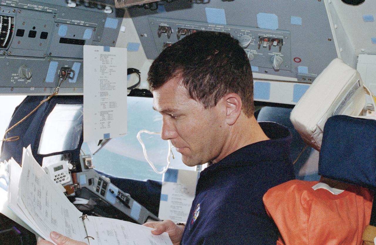STS096-354-030 (27 May - 6 June 1999) --- Astronaut Rick D. Husband,  pilot, reads over the flight data file at the pilot's station on the starboard side of Discovery's forward cabin.  A small portion of Earth's horizon appears through the nearby windshield.