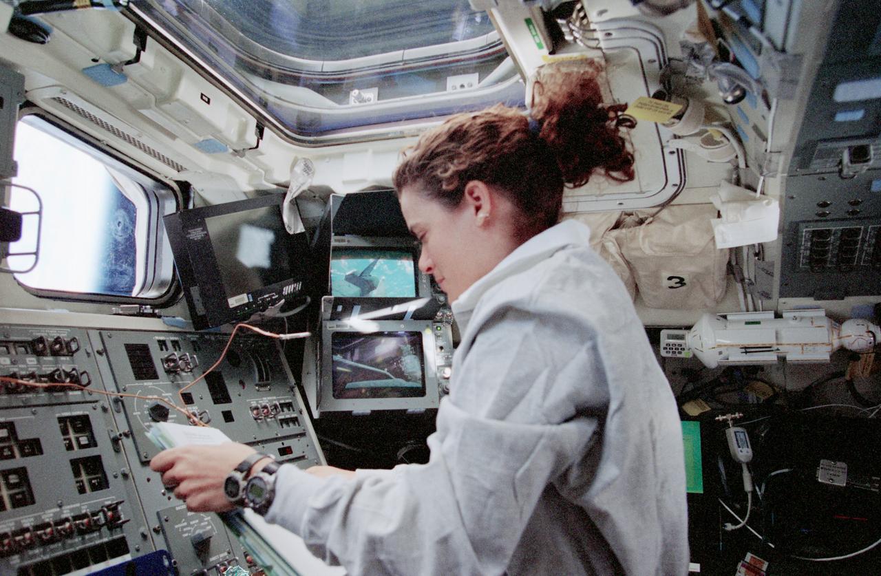 STS096-378-021 (27 May - 6 June 1999) --- Astronaut Julie Payette, mission specialist representing the Candian Space Agency (CSA), operates the Canadian-built remote manipulator system (RMS) from Discovery's aft flight deck. Television monitors nearby afford Payette two different angles of the cargo bay.
