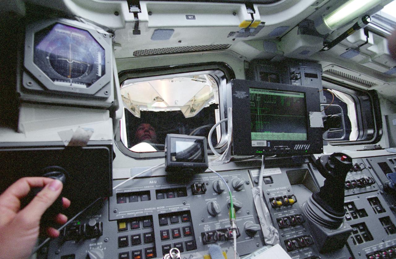 STS096-381-012 (3 June 1999) --- The face of astronaut Rick D. Husband, pilot, is reflected in one of Space Shuttle Discovery's aft flight deck windows as the International Space Station (ISS) leaves the cargo bay.  Husband's hand can be seen on the controls at lower left.  Following the release of the station, Discovery's crew conducted a fly around survey.