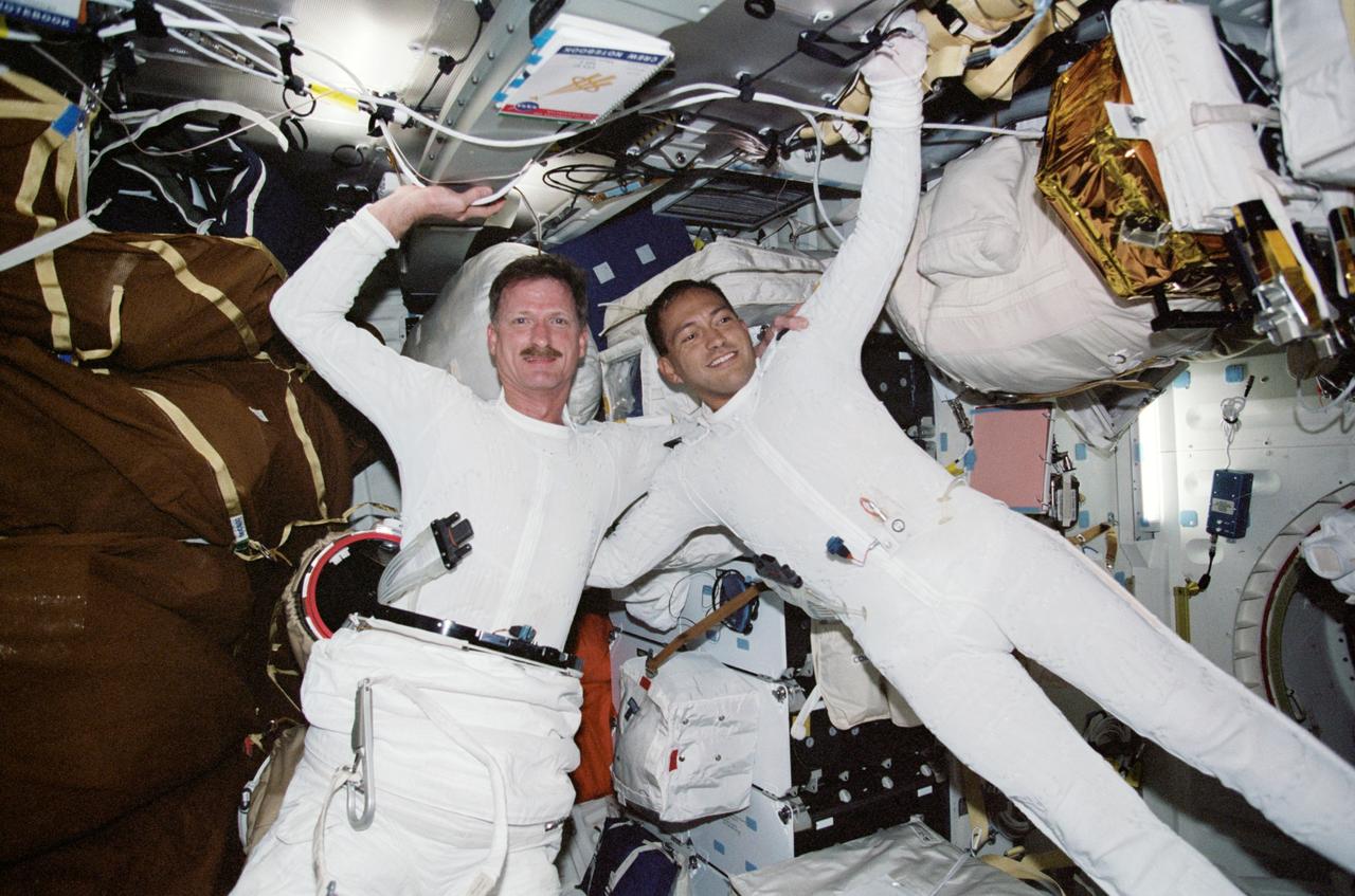 STS097-327-033 (30 Nov.-11 Dec. 2000) --- Astronauts Joseph R. Tanner (left) and Carlos I. Noriega, both mission specialists, who participated in three STS-97 space walks, don their extravehicular mobility unit (EMU) space suits for one of the walks. Tanner and Noriega are wearing the liquid cooling and ventilation garment that complements the EMU.