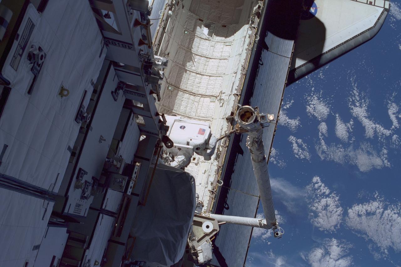 STS097-374-020 (3 December 2000) --- This high angle view shows astronaut Carlos I. Noriega, STS-97 mission specialist, traversing over Endeavour's cargo bay during the flight's first space walk on Dec. 3, 2000.  Astronaut Joseph R. Tanner, mission specialist,  was near the top of the P6 truss structure when he exposed the 35mm frame.  The Canadian-built Remote Manipulator System (RMS) arm can be seen at bottom right.