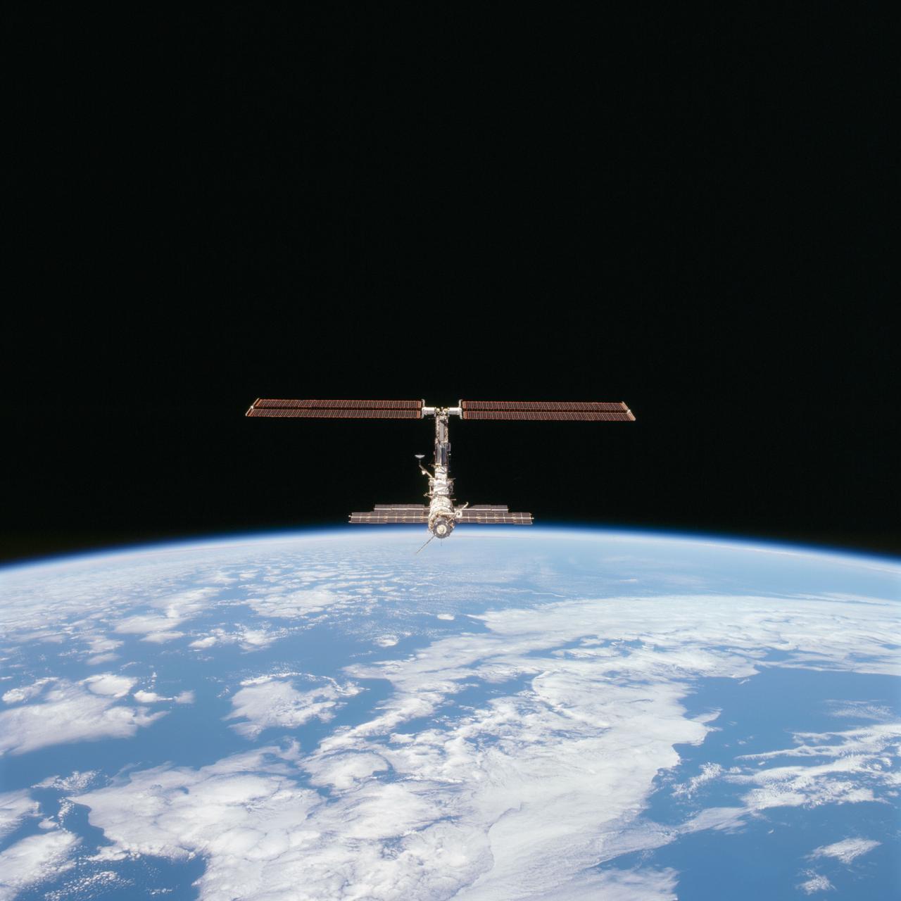 STS097-712-004 (9 December 2000) --- This picture of the distant International Space Station (ISS) blended against the darkness of space and the blue Earth at its horizon is one of a series of 70mm frames exposed of the station following undocking at 1:13 p.m. (CST), December 9, 2000. This series of images, as well as video and digital still imagery taken at the same time, represent the first imagery of the entire station with its new solar array panels deployed, though they are difficult to see in this angle. Before separation, the shuttle and space station had been docked to one another for 6 days, 23 hours and 13 minutes. Endeavour moved downward from the space station, then began a tail-first circle at a distance of about 500 feet. The maneuver, with pilot Michael J. Bloomfield at the controls, took about an hour. While Endeavour flew that circle, the two spacecraft, moving at five miles a second, navigated about two-thirds of the way around the Earth. Undocking took place 235 statute miles above the border of Kazakhstan and China. When Endeavour made its final separation burn, the orbiter and the space station were near the northeastern coast of South America.