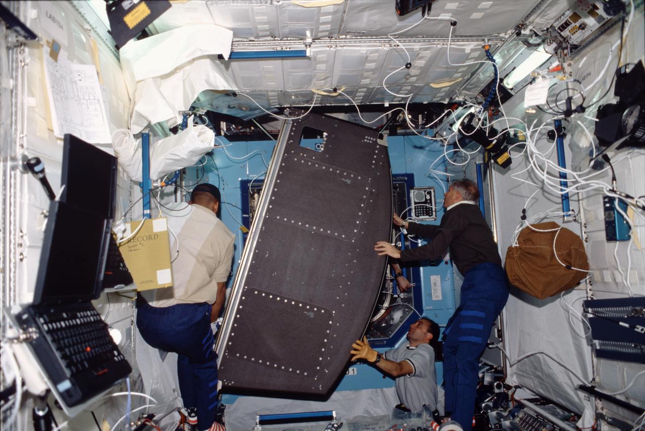 STS098-322-0001 (7-20 February 2001) --- Three STS-98 astronauts move a rack into position aboard the newly attached Destiny laboratory. From the left to right are astronauts Robert L. Curbeam, mission specialist; Mark L. Polansky, pilot; and Kenneth D. Cockrell, mission commander.