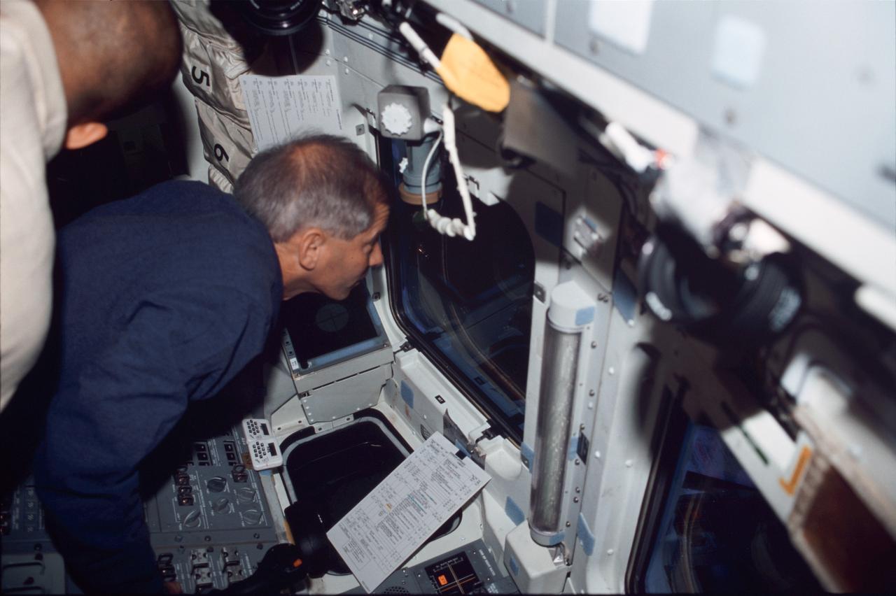 STS098-326-023 (7-20 February 2001) --- Astronaut Kenneth D. Cockrell, mission commander, controls the intricate maneuvers of the shuttle during docking procedures with the International Space Station (ISS) from the aft flight deck of the Space Shuttle Atlantis. Robert L. Curbeam (partially out of frame), mission specialist, can also be seen in this image.