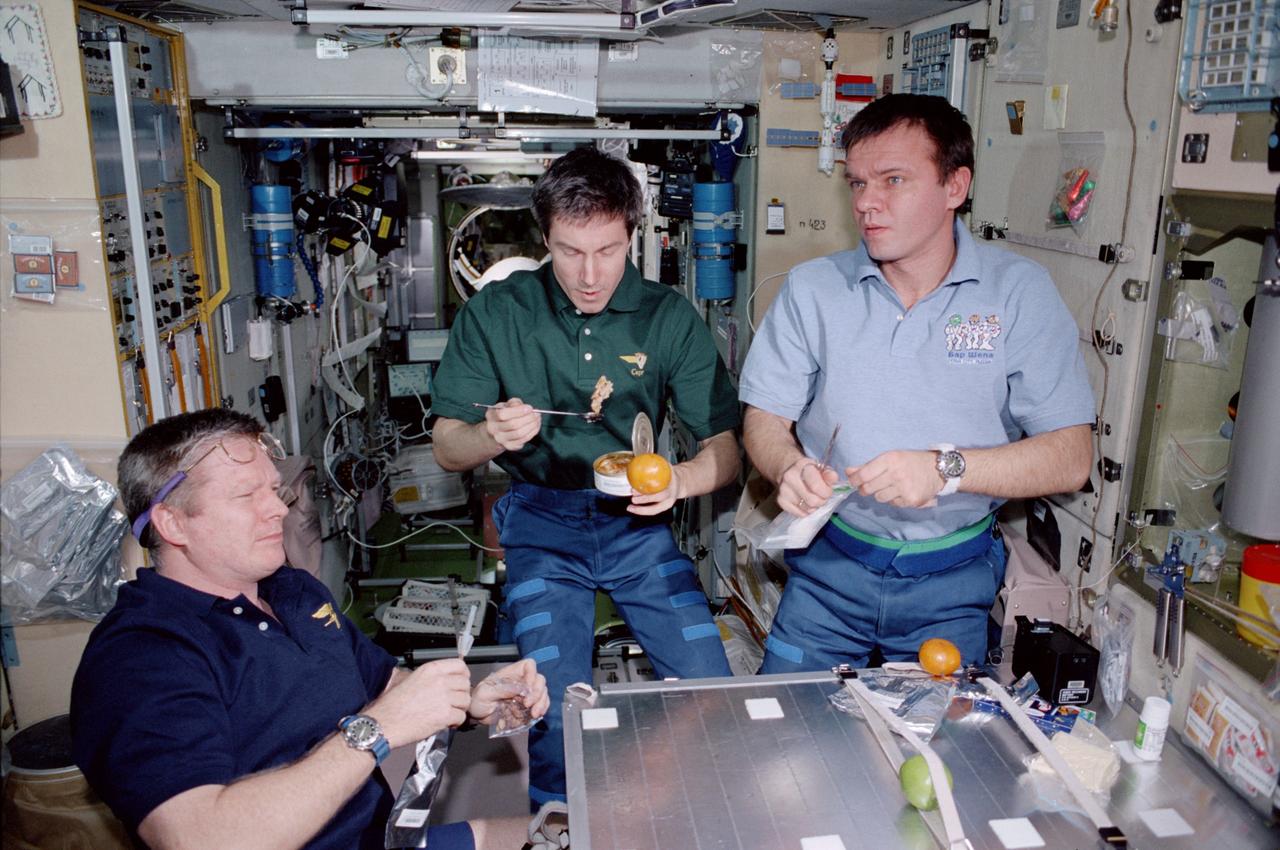 STS098-353-0006 (7-20 February 2001) --- The Expedition One crew enjoys a snack on the ward room table of the Zvezda service module onboard the International Space Station (ISS). The photograph was taken by one of the visiting STS-98 crew members.