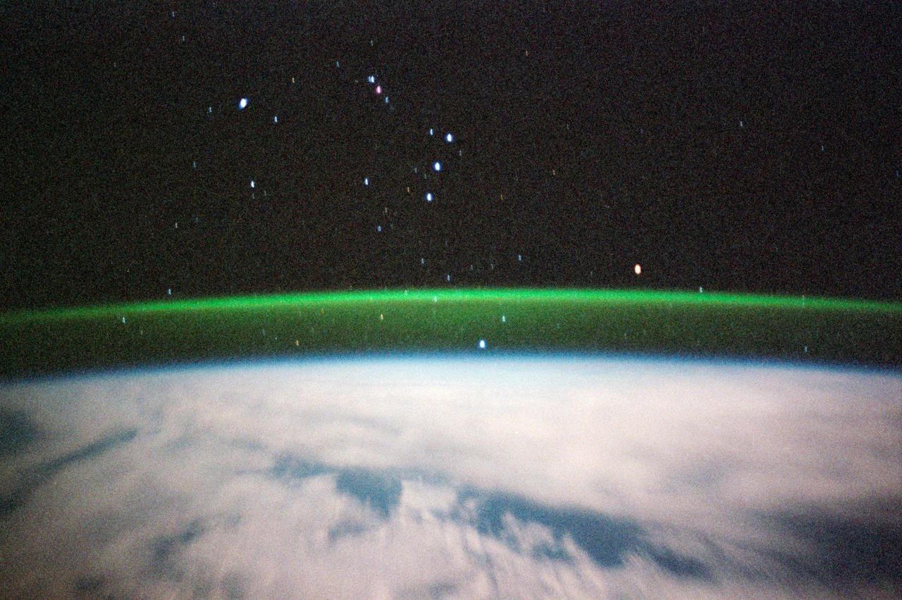 STS099-356-026 (11-22 February 2000) ---Because of its time exposure, this STS-99 35mm frame provides a view of several stars. The thin greenish band above the horizon is airglow; radiation emitted by the atmosphere from a layer about 30 kilometers thick and about 100 kilometers altitude. The predominant emission in airglow is the green 5577-Angstrom wavelength emission from atomic oxygen atoms. Airglow is always and everywhere present in the atmosphere; it results from the recombination of molecules that have been broken apart by solar radiation during the day. But airglow is so faint that it can only be seen at night by looking "edge on" at the emission layer, such as the view astronauts have in orbit.