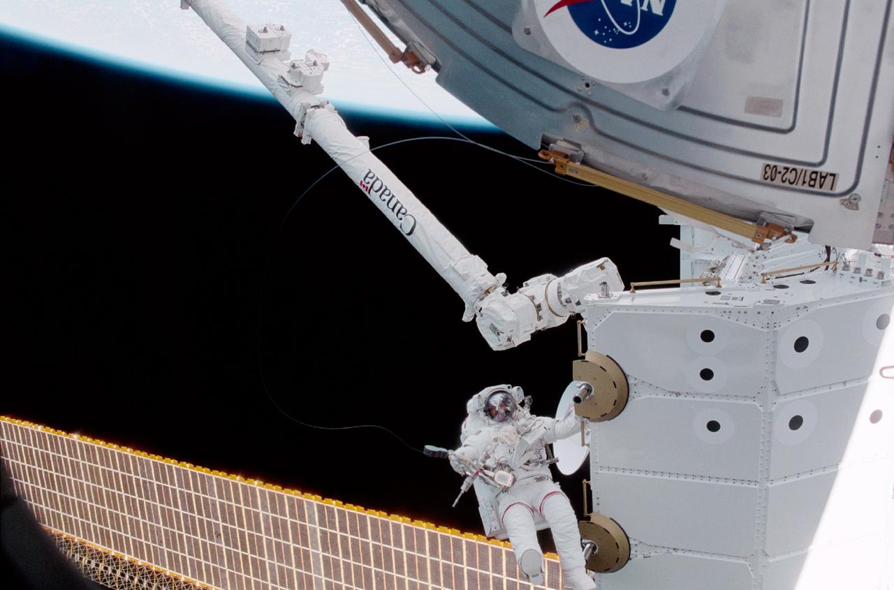 STS100-342-010 (19 April-1 May 2001) --- Astronaut Chris A. Hadfield, mission specialist representing the Canadian Space Agency (CSA), is seen near the Canadarm2 as the new robotics tool for the International Space Station (ISS) grasps the Spacelab pallet. Hadfield participated in two days of extravehicular activity (EVA) on the STS-100 mission.