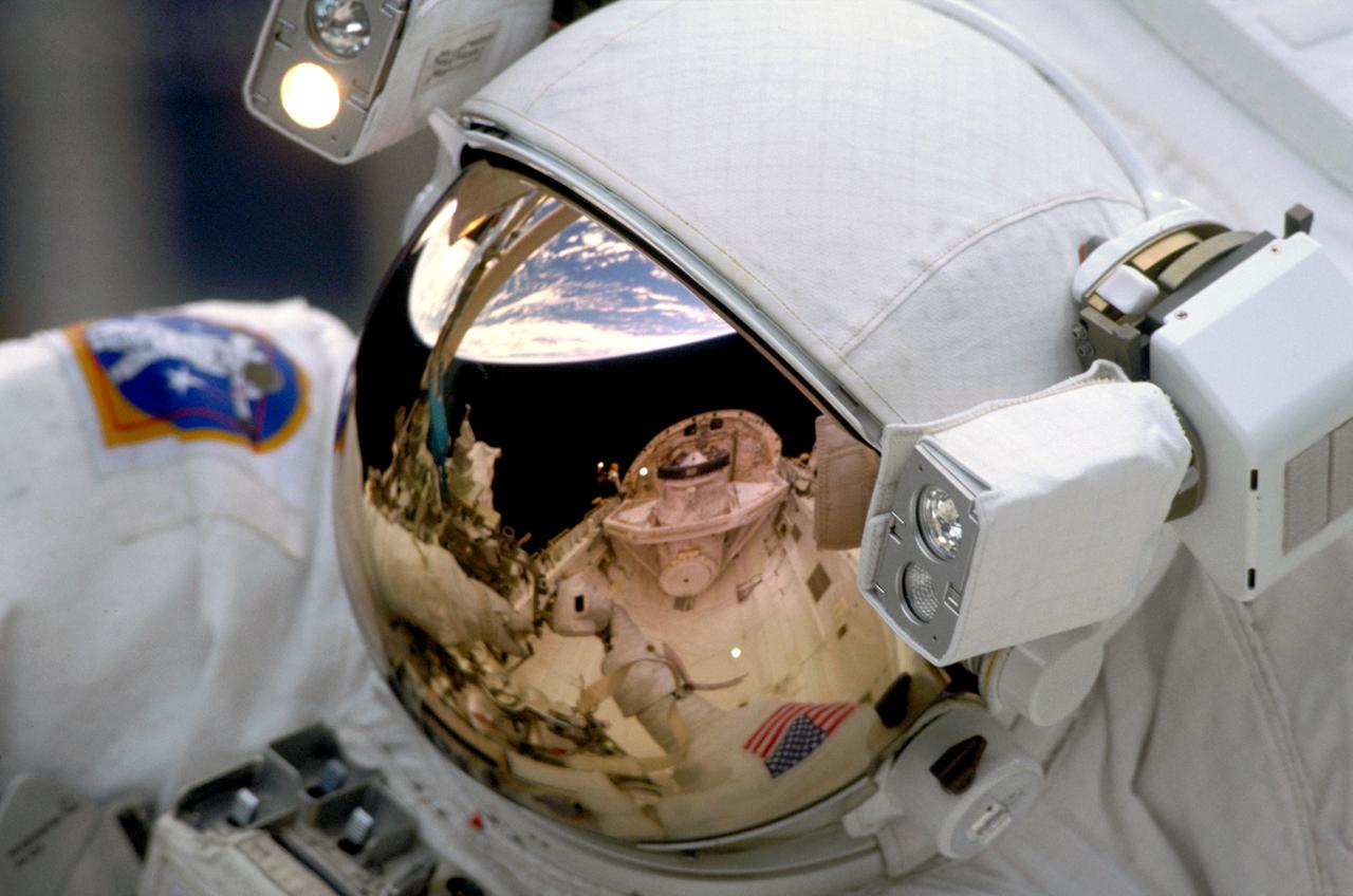 STS103-302-002 (19- 27 December 1999)---.The Space Shuttle Discovery's Cargo Bay and Crew Module, and the Earth's horizon are reflected in the helmet visor of one of the space walking astronauts on STS-103..Astronauts Steven L. Smith, John M. Grunsfeld, C. Michael Foale and Claude Nicollier participated in three days of.extravehicular activity on the NASA's third servicing visit to the Hubble Space Telescope (HST).