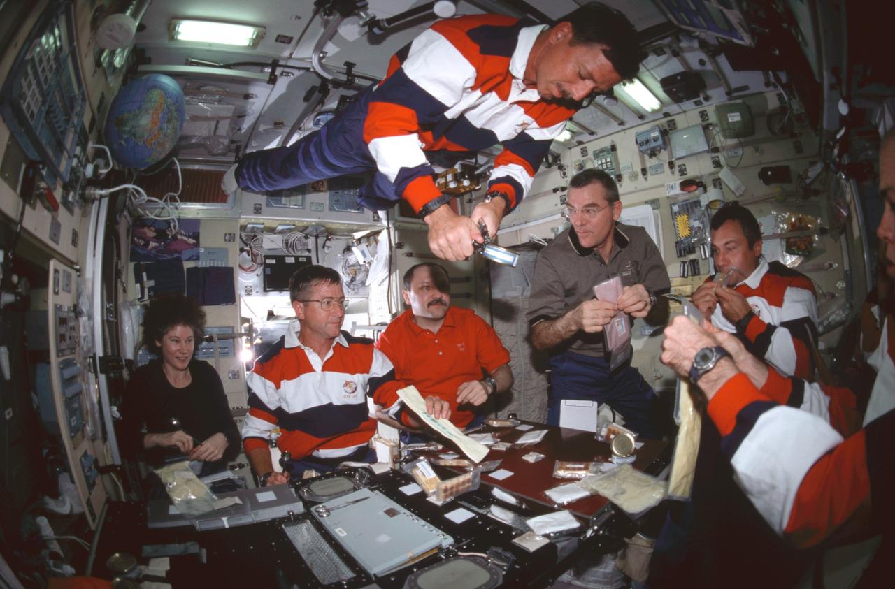 STS105-308-029 (15 August 2001) ---  Astronauts and cosmonauts representing three different crews are just about to share a meal in the Zvezda Service Module on the International Space Station (ISS).  Scott J. Horowitz, STS-105 mission commander, opens a can of food as he floats near the ceiling.  Others from the left are astronaut Susan J. Helms, Expedition Two flight engineer; Frank L. Culbertson, Jr., Expedition Three commander; Yury V. Usachev, Expedition Two commander; James S. Voss, Expedition Two flight engineer and Vladimir N. Dezhurov, Expedition Three flight engineer.  Not pictured are Daniel T. Barry, STS-105 mission specialist; Frederick W. (Rick) Sturckow, STS-105 pilot; Patrick G. Forrester, STS-105 mission specialist; and Mikhail Tyurin, Expedition Three flight engineer.  Dezhurov, Tyurin and Usachev represent Rosaviakosmos.