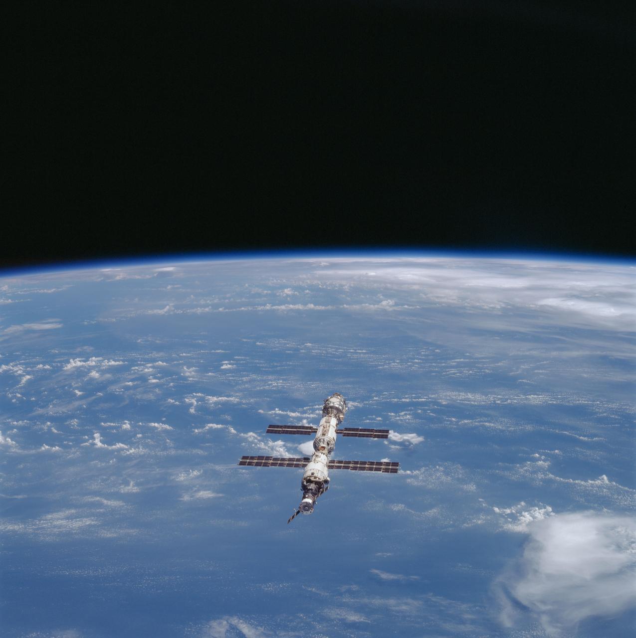 STS106-707-008 (8-20 September 2000) ---- The STS-106 crew members used a  70mm handheld camera to capture this  view of the International Space Station (ISS) over a moderately cloud-covered  land area. The station component nearest the camera is the Progress supply craft, which joined ISS in August 2000.  Progress is docked with the Service Module or Zvezda, which connected to ISS in July 2000.