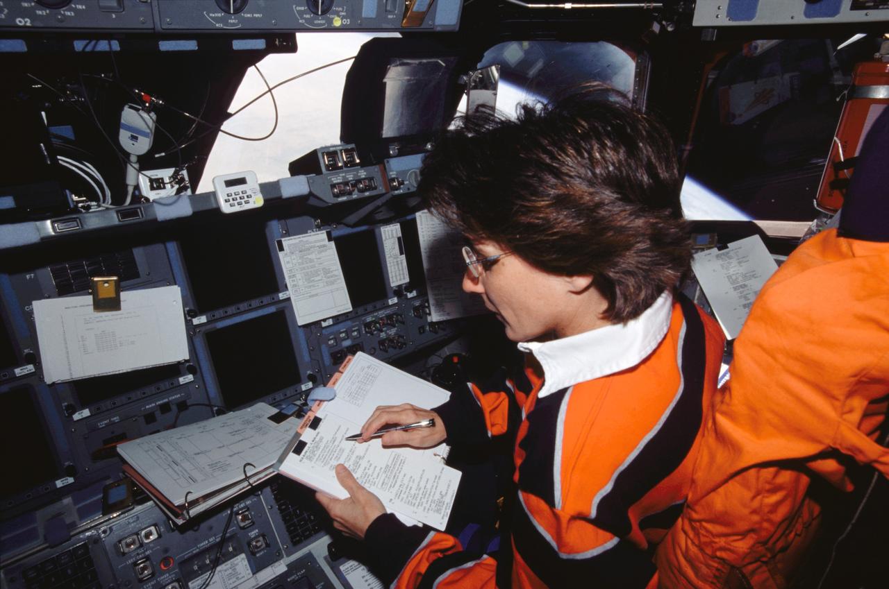 STS109-346-007 (1–;12 March 2002) --- Astronaut Nancy J. Currie, STS-109 mission specialist, looks over a procedures check list while occupying the pilot’;s station on the forward flight deck of the Space Shuttle Columbia.