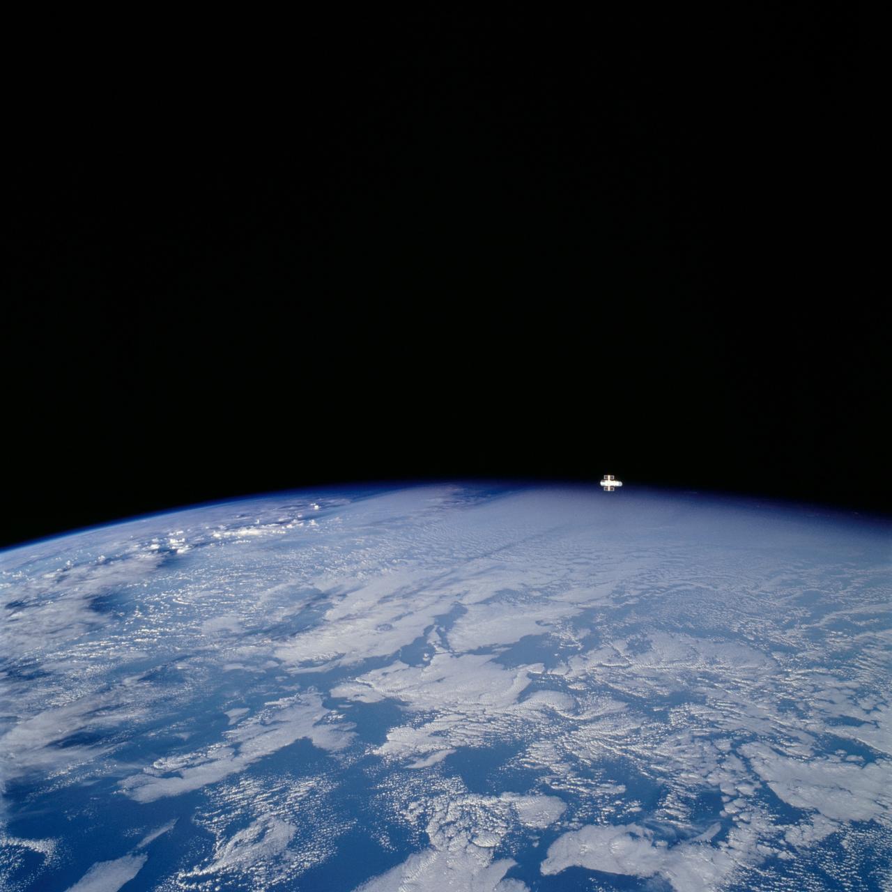 STS109-729-072 (9 March 2002) --- Looking westward, one of the STS-109 crew members photographed the newly serviced and upgraded Hubble Space Telescope (HST) near the earth's limb to the upper right of the center of this 70mm image.  The Space Shuttle Columbia was located over the Atlantic Ocean southwest of the Cape Verde Islands when this image was acquired.  Low to mid-altitude clouds are visible across the image.  Some thunderstorms can be seen near the left center of the image as the sun reflects off the higher cloud tops.
