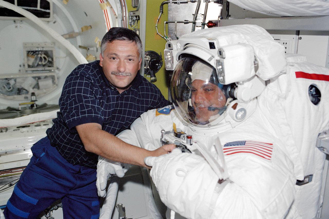 STS112-318-028 (14 October 2002) --- Cosmonaut Fyodor N. Yurchikhin (left), STS-112 mission specialist, assists astronaut David A. Wolf, mission specialist, with the final touches on his Extravehicular Mobility Unit (EMU) space suit in the Quest Airlock on the International Space Station (ISS). Yurchikhin represents Rosaviakosmos.