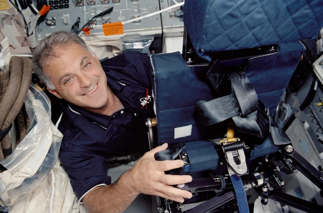 STS112-324-008 (7-18 October 2002) --- Astronaut David A. Wolf, STS-112 mission specialist, works with a temporary flight deck seat, used for launch and entry, on the Space Shuttle Atlantis.