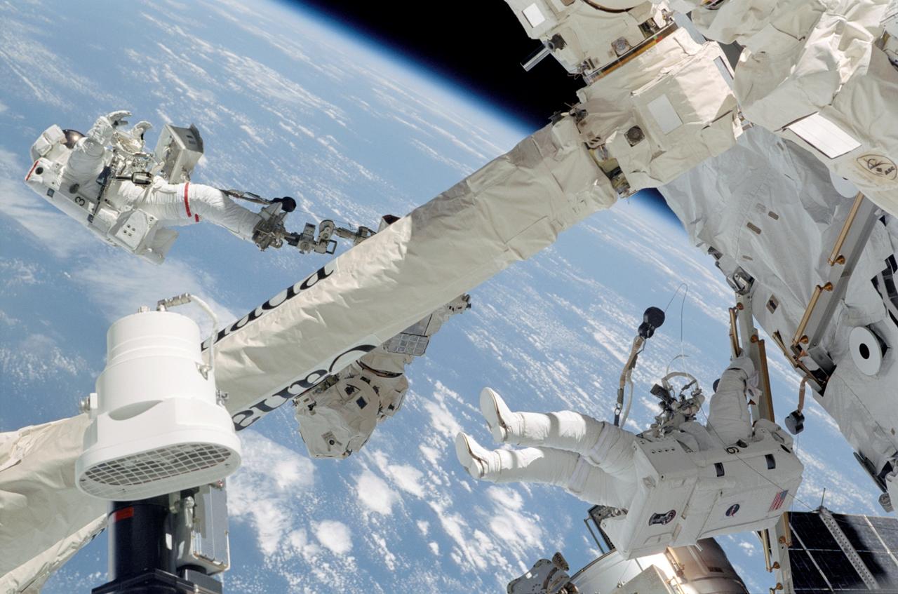 STS112-326-033 (12 October 2002) --- Astronauts David A. Wolf (left) and Piers J. Sellers, both STS-112 mission specialists, participate in the mission&#0146;s second session of extravehicular activity (EVA). Wolf is anchored to a foot restraint on the International Space Station&#0146;s (ISS) Canadarm2 while Sellers traverses along the airlock spur, a route used by spacewalkers to get from the Quest airlock on the station to the outpost's truss.