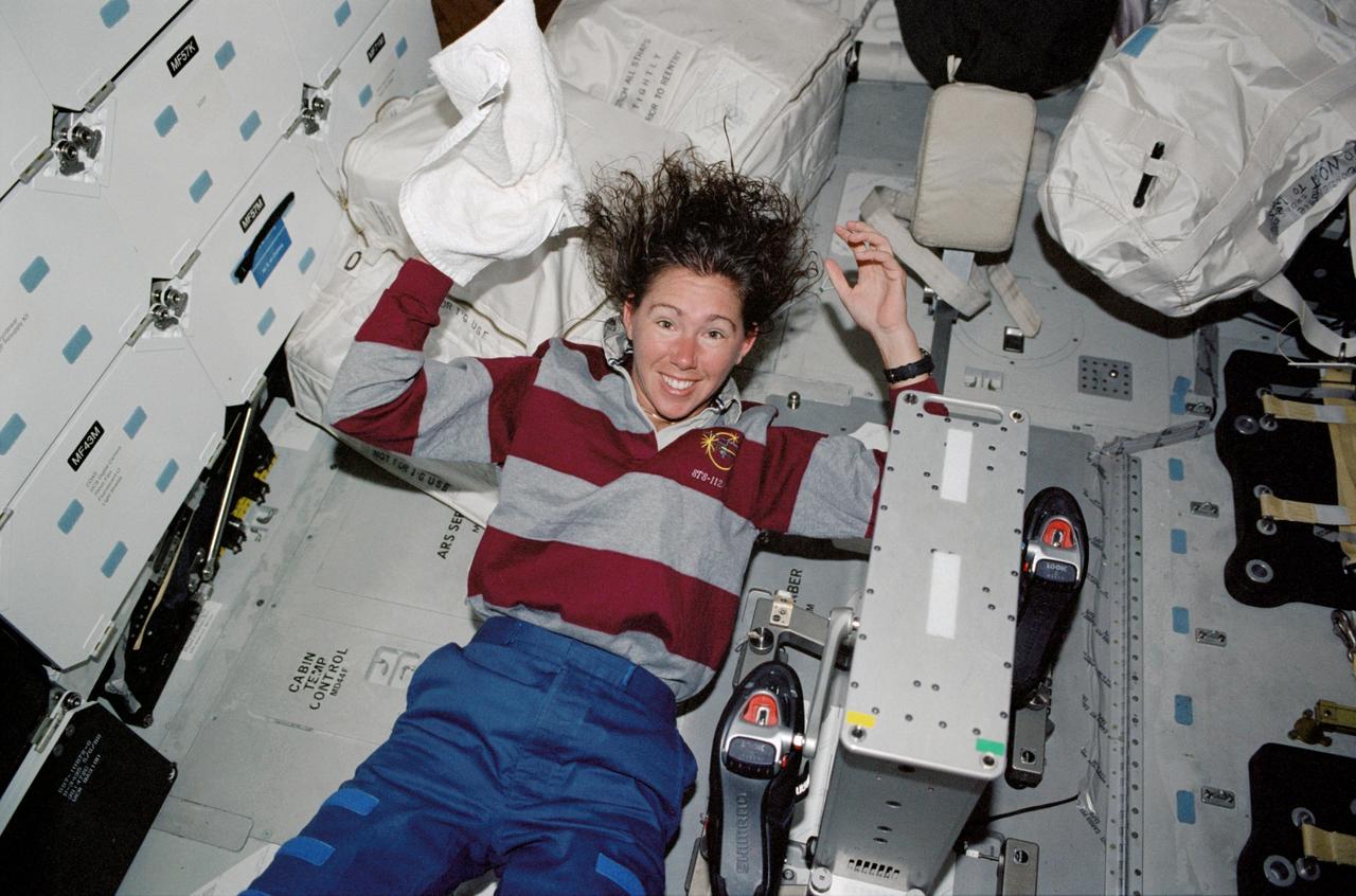 STS112-329-022 (7-18 October 2002) --- Astronaut Sandra H. Magnus, STS-112 mission specialist, washes her hair near a bicycle ergometer on the middeck of the Space Shuttle Atlantis.