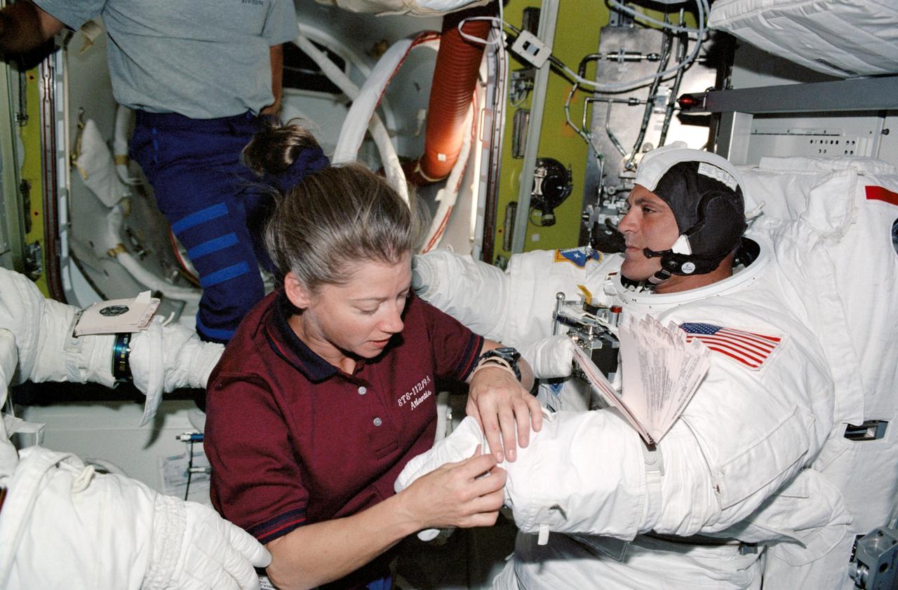 STS112-332-002 (12 October 2002) --- Astronaut Pamela A. Melroy, STS-112 pilot, assists astronaut David A. Wolf, mission specialist, with the final touches on his Extravehicular Mobility Unit (EMU) spacesuit prior to the mission&#0146;s second session of extravehicular activity (EVA). Astronaut Piers J. Sellers (partially out of frame), mission specialist, joined Wolf on the spacewalk.