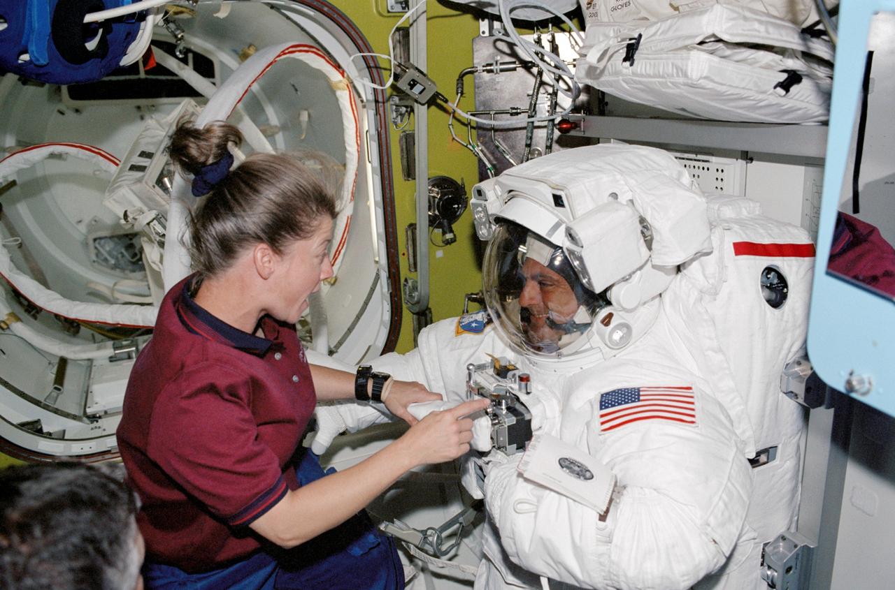 STS112-332-014 (12 October 2002) --- Astronaut Pamela A. Melroy, STS-112 pilot, assists astronaut David A. Wolf, mission specialist, with the final touches on his Extravehicular Mobility Unit (EMU) spacesuit prior to the mission&#0146;s second session of extravehicular activity (EVA).
