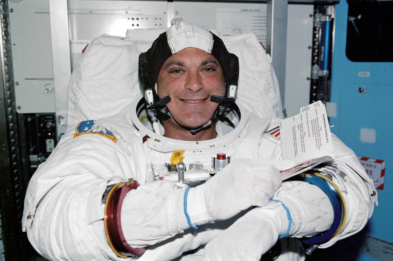 STS112-336-020 (12 October 2002) --- Astronaut David A. Wolf, STS-112 mission specialist, looks over a procedures checklist in the Quest Airlock on the International Space Station (ISS). Wolf is attired in his Extravehicular Mobility Unit (EMU) spacesuit.