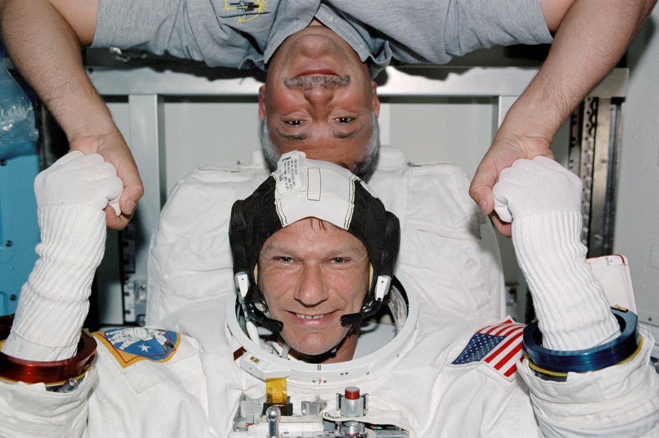 STS112-336-022 (12 October 2002) --- Astronaut Piers J. Sellers (bottom) and cosmonaut Fyodor N. Yurchikhin, both STS-112 mission specialists, pose for a 180-degree head-to-head photo in the Quest Airlock on the International Space Station (ISS). Sellers is attired in his Extravehicular Mobility Unit (EMU) spacesuit. Sellers and astronaut David A. Wolf (out of frame) were preparing to exit the station&#0146;s airlock for the mission&#0146;s second spacewalk.  Yurchikhin represents Rosaviakosmos.