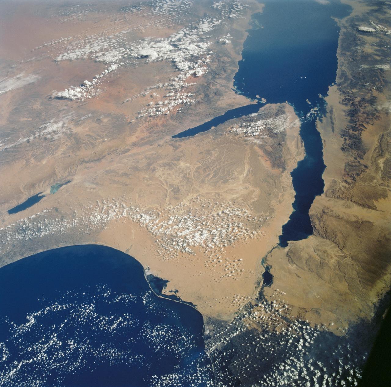 STS112-702-002  (7-18 October 2002) --- Egypt's triangular Sinai Peninsula lies in the center of this view,  photographed from the Space Shuttle Atlantis, with the dark greens of the Nile delta lower right.  In this southwesterly  view,  the Red Sea, with its characteristic parallel coastlines, stretches toward the top.  At the bottom of the image,  the Suez Canal appears as an irregular line joining the Red Sea to the Mediterranean Sea (lower left).  The Dead Sea in central Israel, with its light blue salt ponds at the south end, appears on the left margin.