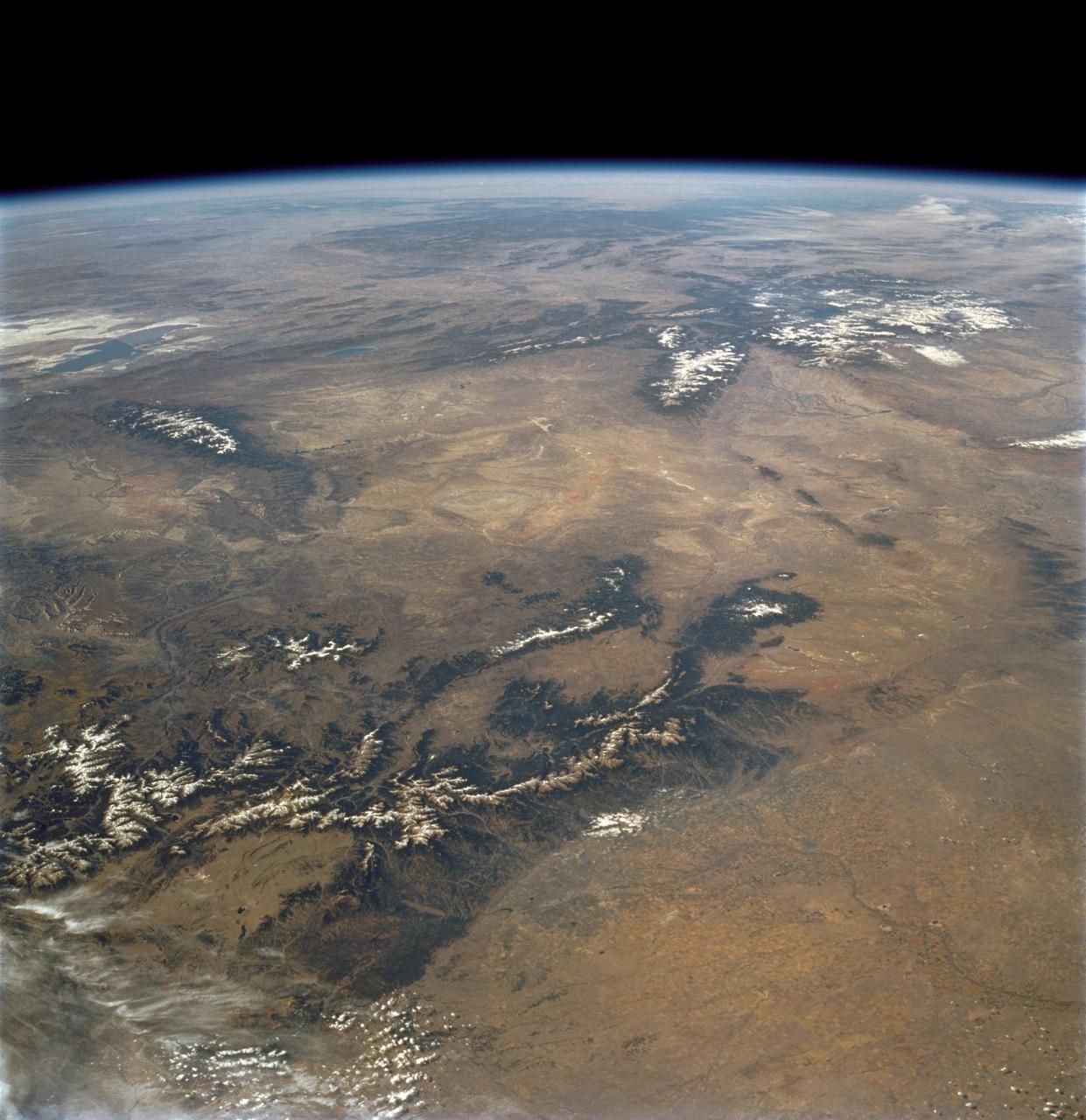 STS112-708-002 (7-18 October 2002) --- This image, photographed from the Earth-orbiting Space Shuttle Atlantis, covers parts of Utah, Colorado, Wyoming and Idaho. The Front Range of the Rockies is the dark range crossing the bottom of the view, with Denver and neighboring cities (grays) situated in the gentle embayment of the mountains (bottom center of the view). Great Salt Lake in Utah appears as two colors of blue top left, with the snow-covered Uinta Mountains just below, in this northwesterly view. Most of the view encompasses the brown plains of western Wyoming (center) and the cluster of mountains around Yellowstone (top center, top right, with snow). Beyond the brown Snake River Plain, black rocks of the Sawtooth Mountains and neighboring ranges of central Idaho appear top center.