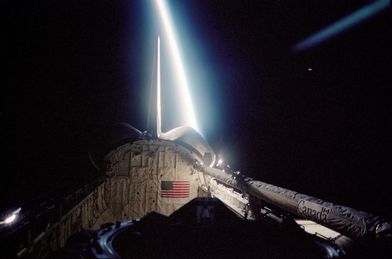 STS113-347-003 (23 November – 7 December 2002) --- View of the Space Shuttle Endeavour’s payload bay with the remote manipulator system (RMS) robotic arm in lower right frame. The blackness of space, Earth’s moon (upper right frame), and a thin slice of Earth’s horizon which runs vertically across the photograph, form the backdrop for this photograph.