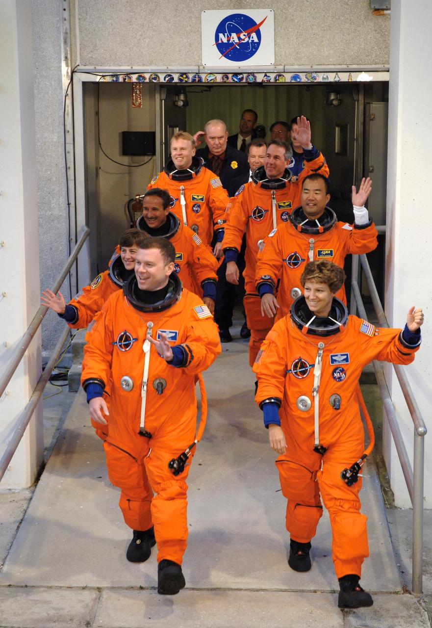STS114-S-006 (26 July 2005) --- The STS-114 crew members, having donned their launch and entry suits, wave at KSC employees as they head out to the transfer van awaiting to take them to Launch Pad 39B. Eileen M. Collins, commander, leads the way. James M. Kelly, pilot, is at front left. Other crew members -- Wendy Lawrence, Andrew S.W. Thomas, Stephen K. Robinson, Charles J. Camarda and JAXA astronaut Soichi Noguchi--follow.