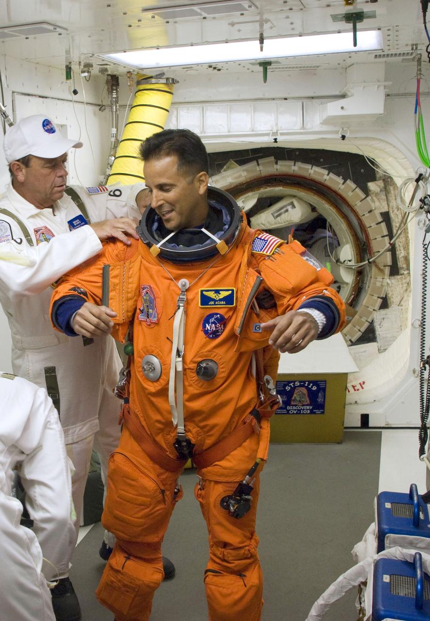 STS119-S-014 (15 March 2009) ---  In the White Room on launch pad 39A at NASA's Kennedy Space Center in Florida, astronaut Joseph Acaba, STS-119 mission specialist, attired in his shuttle launch and entry suit, dons his harness, which includes a parachute pack, before crawling through the open hatch into Space Shuttle Discovery. The White Room is at the end of the orbiter access arm on the fixed service structure and provides access into the shuttle. Members of the closeout crew assisted Acaba. Liftoff is scheduled for 7:43 p.m. (EDT) on March 15, 2009.