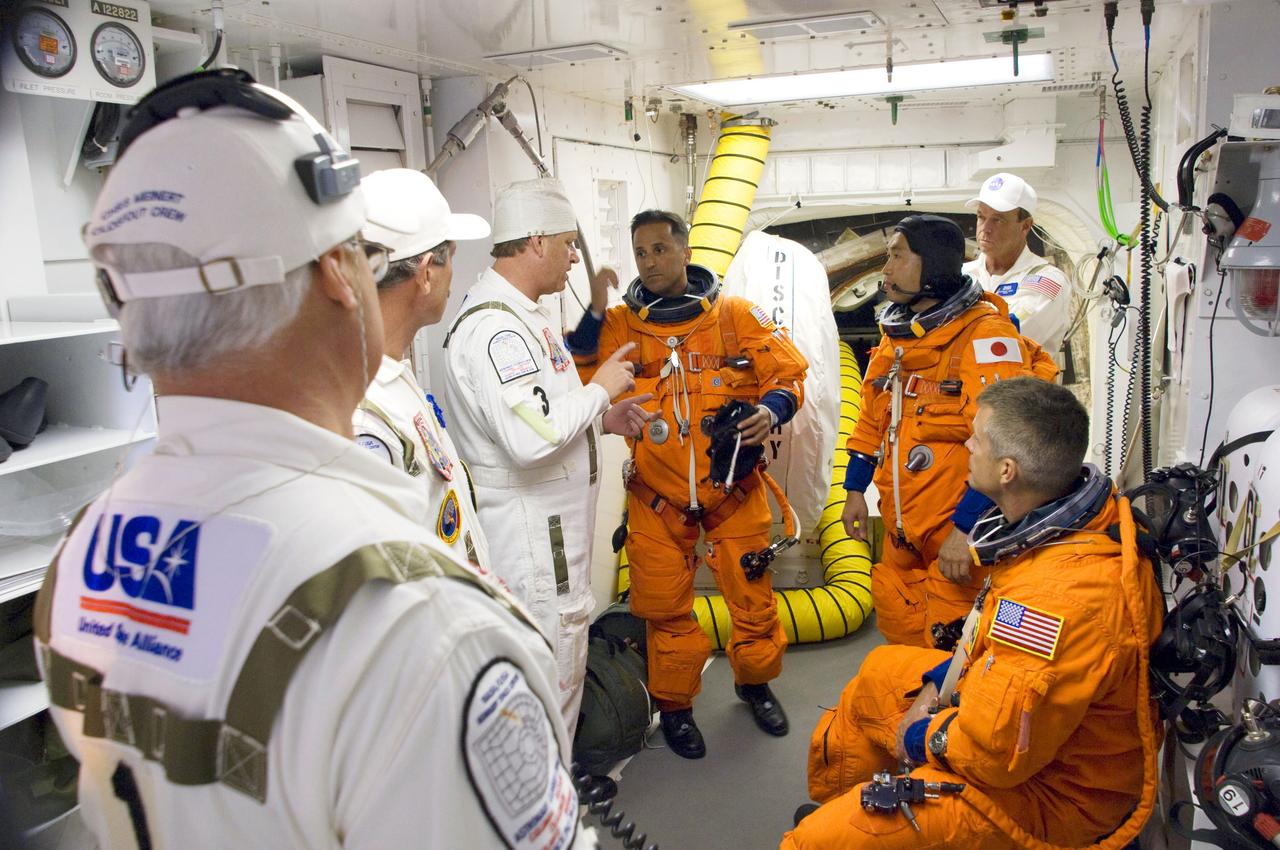 STS119-S-016 (15 March 2009) --- In the White Room on launch pad 39A at NASA's Kennedy Space Center in Florida, attired in their shuttle launch and entry suits with harness and parachute pack, astronauts Joseph Acaba (left), Japan Aerospace Exploration Agency’s Koichi Wakata (center) and Steve Swanson (seated) talk with the closeout crew as they prepare to go through the open hatch into Space Shuttle Discovery. The White Room is at the end of the orbiter access arm on the fixed service structure and provides access into the shuttle. Liftoff is scheduled for 7:43 p.m. (EDT) on March 15, 2009.