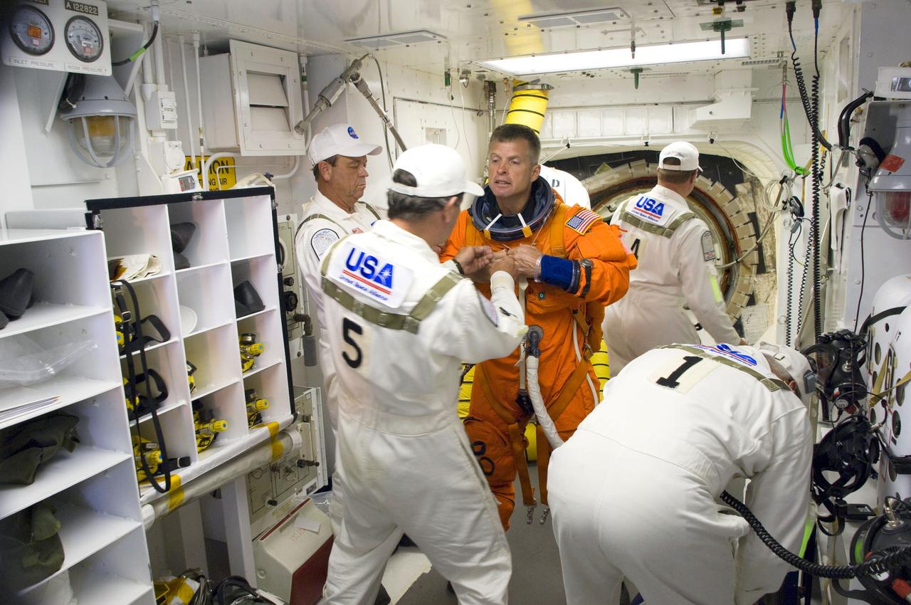 STS119-S-017 (15 March 2009) --- In the White Room on launch pad 39A at NASA's Kennedy Space Center in Florida, astronaut Steve Swanson, STS-119 mission specialist, attired in his shuttle launch and entry suit, dons his harnesses, which includes a parachute pack, before crawling through the open hatch into Space Shuttle Discovery. The White Room is at the end of the orbiter access arm on the fixed service structure and provides access into the shuttle. Members of the closeout crew assisted Swanson. Liftoff is scheduled for 7:43 p.m. (EDT) on March 15, 2009.