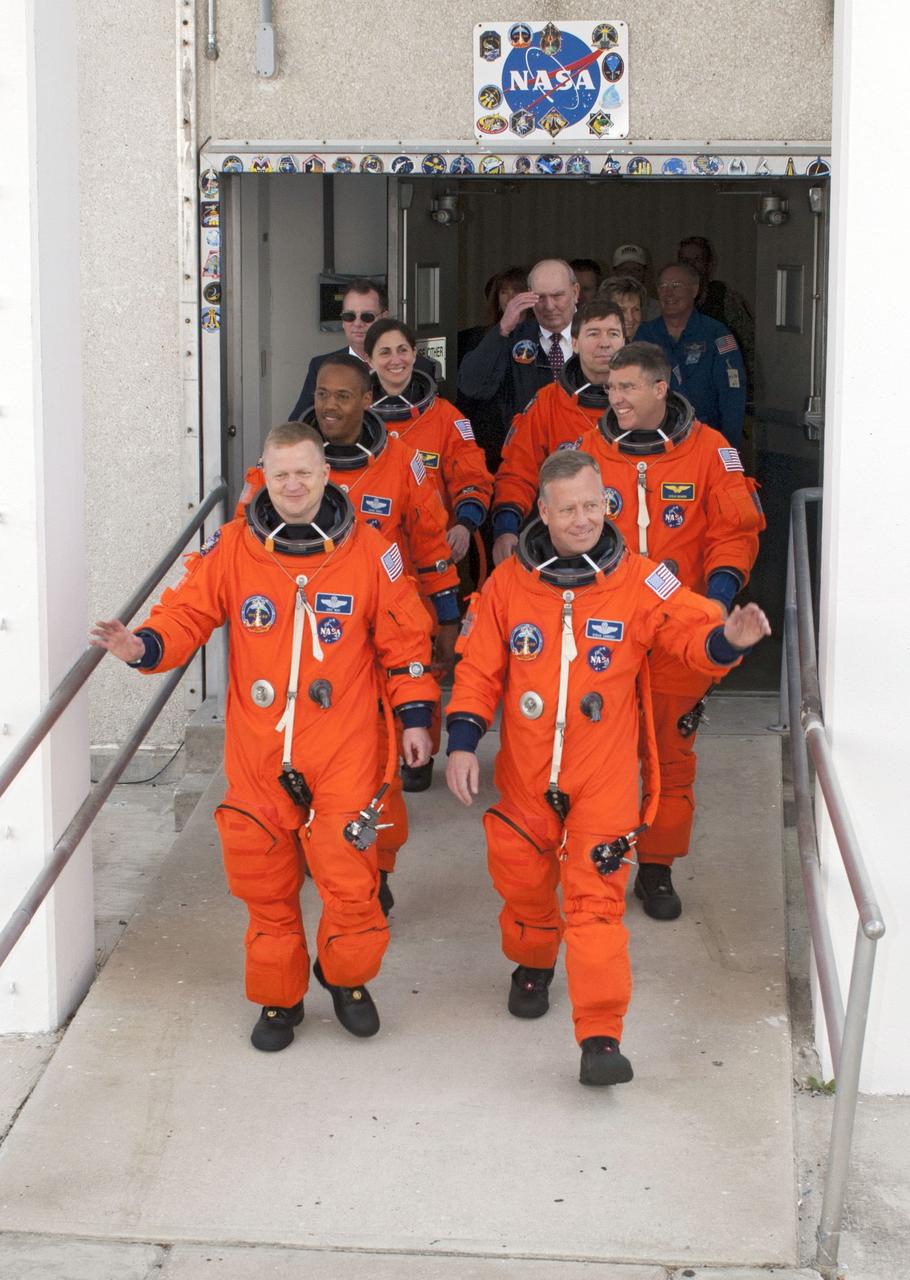 STS133-S-005 (24 Feb. 2011) --- After suiting up, the STS-133 crew members exit the Operations and Checkout Building to board the Astrovan, which will take them to launch pad 39A for the launch of space shuttle Discovery on the STS-133 mission. On the right (front to back) are NASA astronauts Steve Lindsey, commander; Steve Bowen and Michael Barratt, both mission specialists. On the left (front to back) are NASA astronauts Eric Boe, pilot; Alvin Drew and Nicole Stott, both mission specialists. Discovery and its six-member crew will deliver the Permanent Multipurpose Module, packed with supplies and critical spare parts, as well as Robonaut 2, the dexterous humanoid astronaut helper, to the International Space Station. Discovery, which will fly its 39th mission, is scheduled to be retired following STS-133. This will be the 133rd Space Shuttle Program mission and the 35th shuttle voyage to the space station. Photo credit: NASA or National Aeronautics and Space Administration