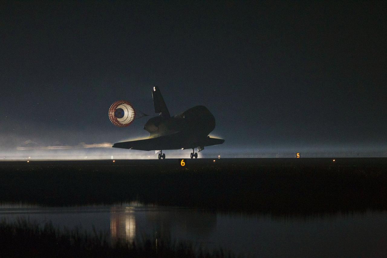 STS135-S-252 (21 July 2011) --- Space shuttle Atlantis' drag chute slows the shuttle as it lands on Runway 15 at the Shuttle Landing Facility at NASA's Kennedy Space Center in Florida. Securing the space shuttle fleet's place in history, Atlantis marked the 26th nighttime landing of NASA's Space Shuttle Program and the 78th landing at Kennedy. Main gear touchdown was at 5:57:00 a.m. (EDT) on July 21, 2011, followed by nose gear touchdown at 5:57:20 a.m., and wheelstop at 5:57:54 a.m. Onboard are NASA astronauts Chris Ferguson, STS-135 commander; Doug Hurley, pilot; Sandy Magnus and Rex Walheim, both mission specialists. On the 37th shuttle mission to the International Space Station, STS-135 delivered more than 9,400 pounds of spare parts, equipment and supplies in the Raffaello multi-purpose logistics module that will sustain station operations for the next year. STS-135 was the 33rd and final flight for Atlantis, which has spent 307 days in space, orbited Earth 4,848 times and traveled 125,935,769 miles. Photo credit: NASA
