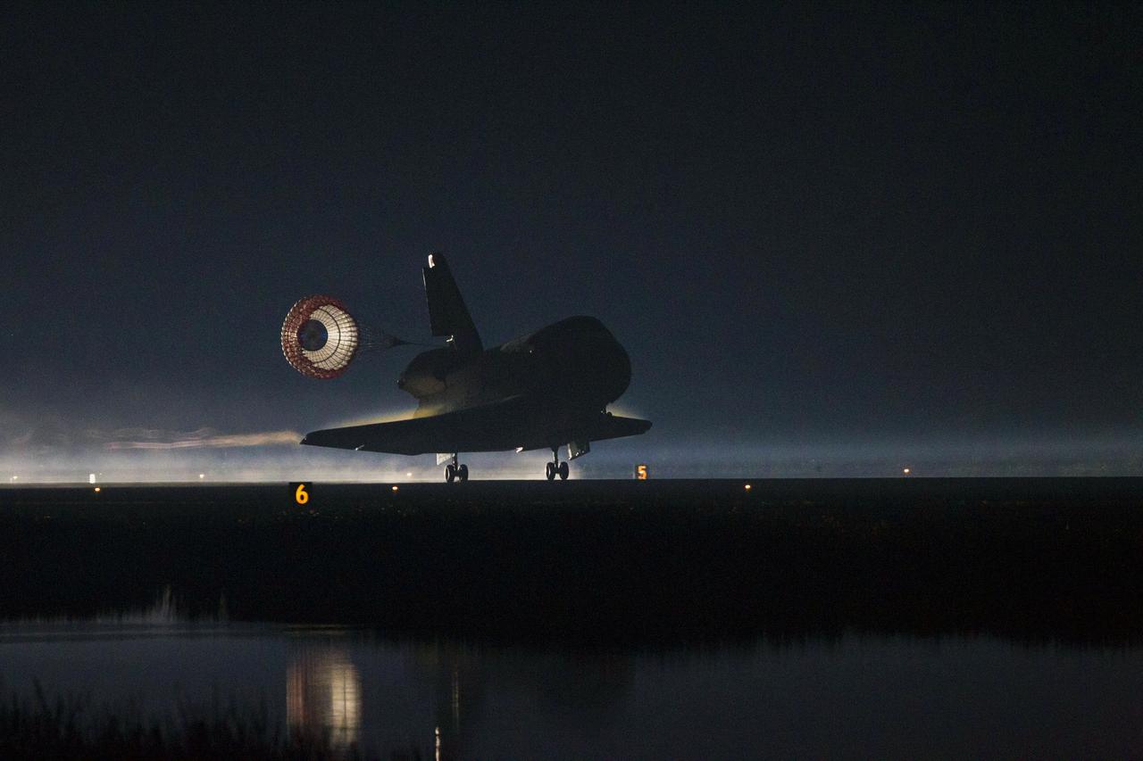 STS135-S-253 (21 July 2011) --- Space shuttle Atlantis' drag chute slows the shuttle as it lands on Runway 15 at the Shuttle Landing Facility at NASA's Kennedy Space Center in Florida. Securing the space shuttle fleet's place in history, Atlantis marked the 26th nighttime landing of NASA's Space Shuttle Program and the 78th landing at Kennedy. Main gear touchdown was at 5:57:00 a.m. (EDT) on July 21, 2011, followed by nose gear touchdown at 5:57:20 a.m., and wheelstop at 5:57:54 a.m. Onboard are NASA astronauts Chris Ferguson, STS-135 commander; Doug Hurley, pilot; Sandy Magnus and Rex Walheim, both mission specialists. On the 37th shuttle mission to the International Space Station, STS-135 delivered more than 9,400 pounds of spare parts, equipment and supplies in the Raffaello multi-purpose logistics module that will sustain station operations for the next year. STS-135 was the 33rd and final flight for Atlantis, which has spent 307 days in space, orbited Earth 4,848 times and traveled 125,935,769 miles. Photo credit: NASA
