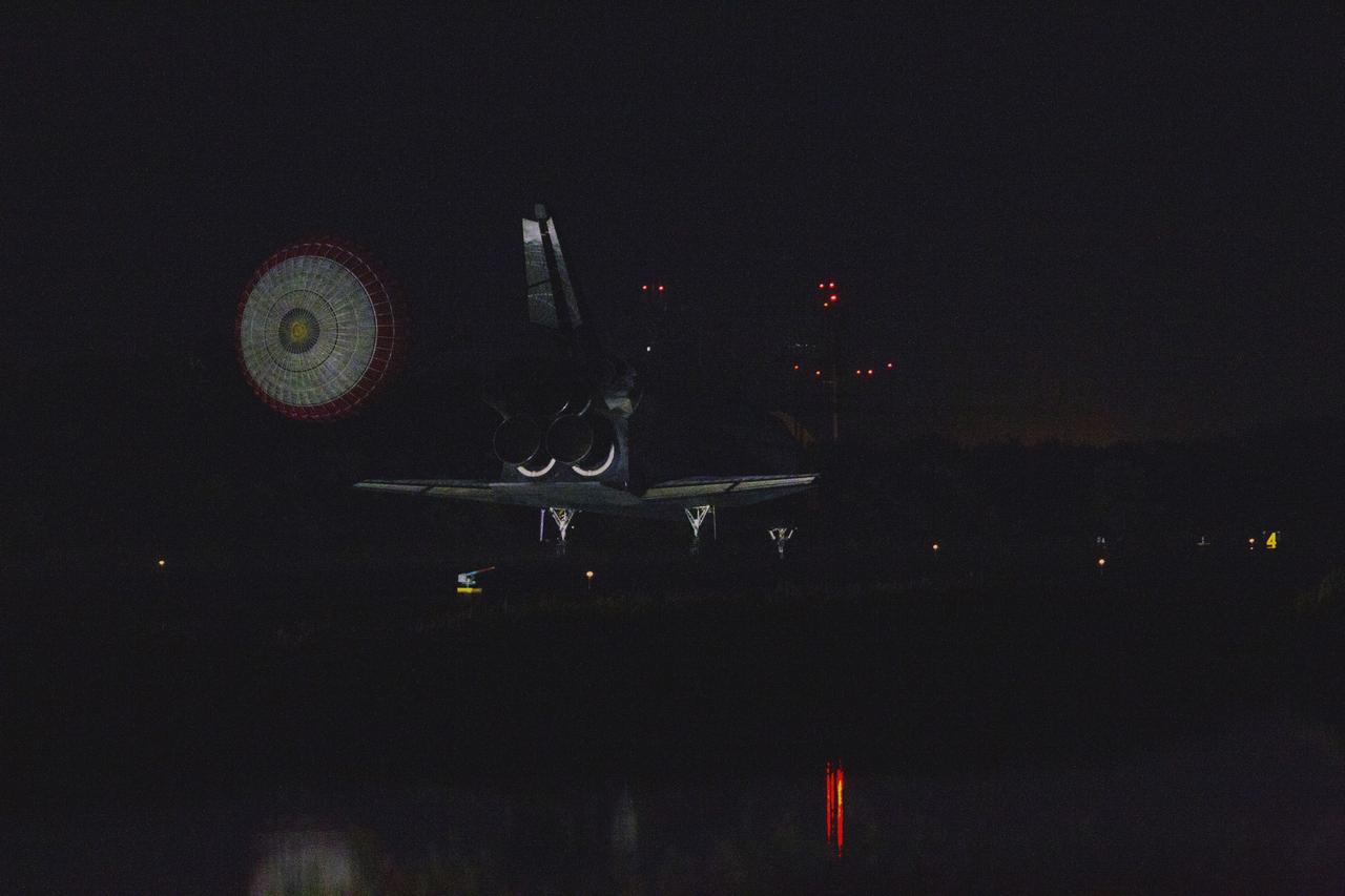 STS135-S-258 (21 July 2011) --- Space shuttle Atlantis' drag chute slows the shuttle as it lands on Runway 15 at the Shuttle Landing Facility at NASA's Kennedy Space Center in Florida. Securing the space shuttle fleet's place in history, Atlantis marked the 26th nighttime landing of NASA's Space Shuttle Program and the 78th landing at Kennedy. Main gear touchdown was at 5:57:00 a.m. (EDT) on July 21, 2011, followed by nose gear touchdown at 5:57:20 a.m., and wheelstop at 5:57:54 a.m. Onboard are NASA astronauts Chris Ferguson, STS-135 commander; Doug Hurley, pilot; Sandy Magnus and Rex Walheim, both mission specialists. On the 37th shuttle mission to the International Space Station, STS-135 delivered more than 9,400 pounds of spare parts, equipment and supplies in the Raffaello multi-purpose logistics module that will sustain station operations for the next year. STS-135 was the 33rd and final flight for Atlantis, which has spent 307 days in space, orbited Earth 4,848 times and traveled 125,935,769 miles. Photo credit: NASA
