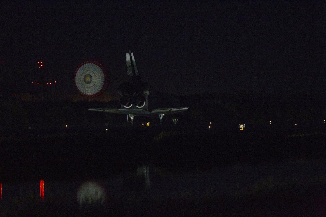 STS135-S-260 (21 July 2011) --- Space shuttle Atlantis' drag chute slows the shuttle as it lands on Runway 15 at the Shuttle Landing Facility at NASA's Kennedy Space Center in Florida. Securing the space shuttle fleet's place in history, Atlantis marked the 26th nighttime landing of NASA's Space Shuttle Program and the 78th landing at Kennedy. Main gear touchdown was at 5:57:00 a.m. (EDT) on July 21, 2011, followed by nose gear touchdown at 5:57:20 a.m., and wheelstop at 5:57:54 a.m. Onboard are NASA astronauts Chris Ferguson, STS-135 commander; Doug Hurley, pilot; Sandy Magnus and Rex Walheim, both mission specialists. On the 37th shuttle mission to the International Space Station, STS-135 delivered more than 9,400 pounds of spare parts, equipment and supplies in the Raffaello multi-purpose logistics module that will sustain station operations for the next year. STS-135 was the 33rd and final flight for Atlantis, which has spent 307 days in space, orbited Earth 4,848 times and traveled 125,935,769 miles. Photo credit: NASA