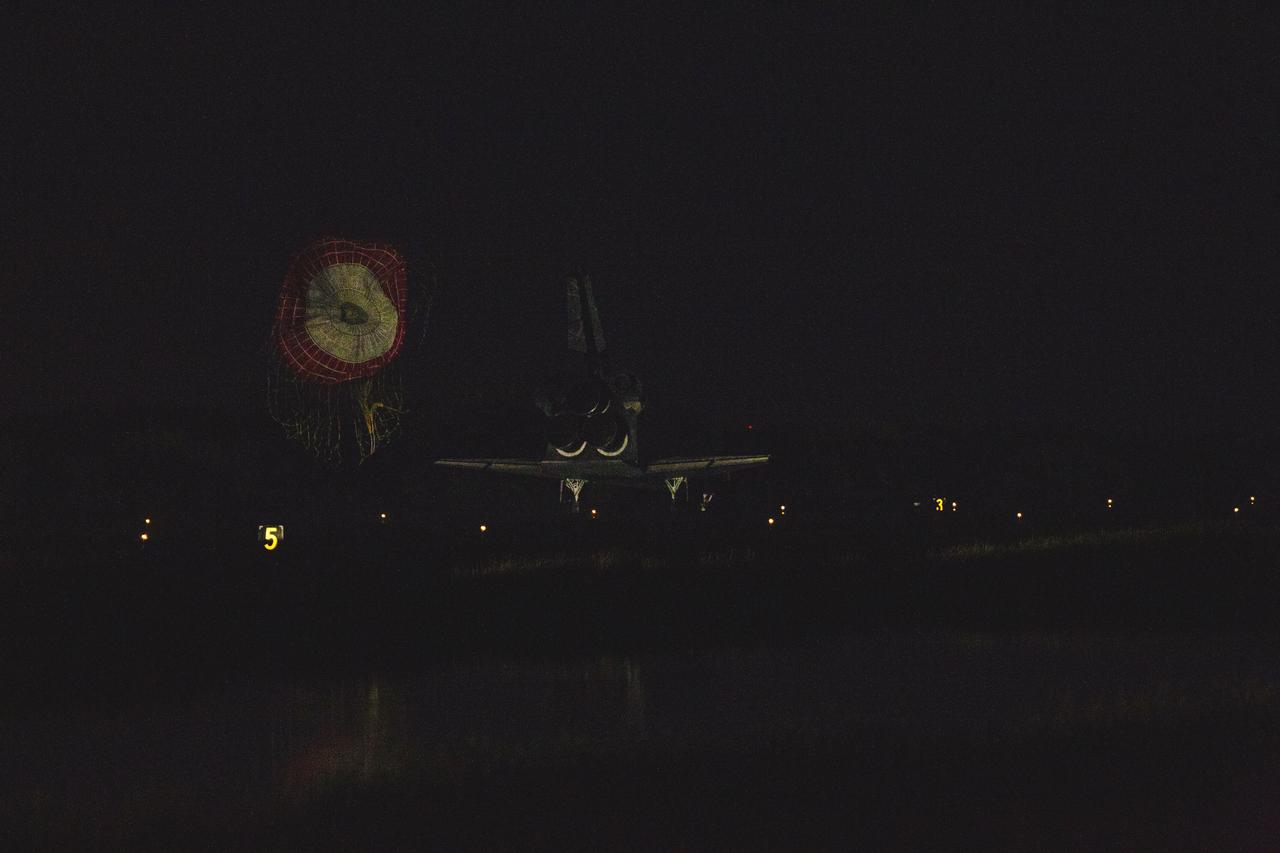 STS135-S-262 (21 July 2011) --- Space shuttle Atlantis' drag chute slows the shuttle as it lands on Runway 15 at the Shuttle Landing Facility at NASA's Kennedy Space Center in Florida. Securing the space shuttle fleet's place in history, Atlantis marked the 26th nighttime landing of NASA's Space Shuttle Program and the 78th landing at Kennedy. Main gear touchdown was at 5:57:00 a.m. (EDT) on July 21, 2011, followed by nose gear touchdown at 5:57:20 a.m., and wheelstop at 5:57:54 a.m. Onboard are NASA astronauts Chris Ferguson, STS-135 commander; Doug Hurley, pilot; Sandy Magnus and Rex Walheim, both mission specialists. On the 37th shuttle mission to the International Space Station, STS-135 delivered more than 9,400 pounds of spare parts, equipment and supplies in the Raffaello multi-purpose logistics module that will sustain station operations for the next year. STS-135 was the 33rd and final flight for Atlantis, which has spent 307 days in space, orbited Earth 4,848 times and traveled 125,935,769 miles. Photo credit: NASA