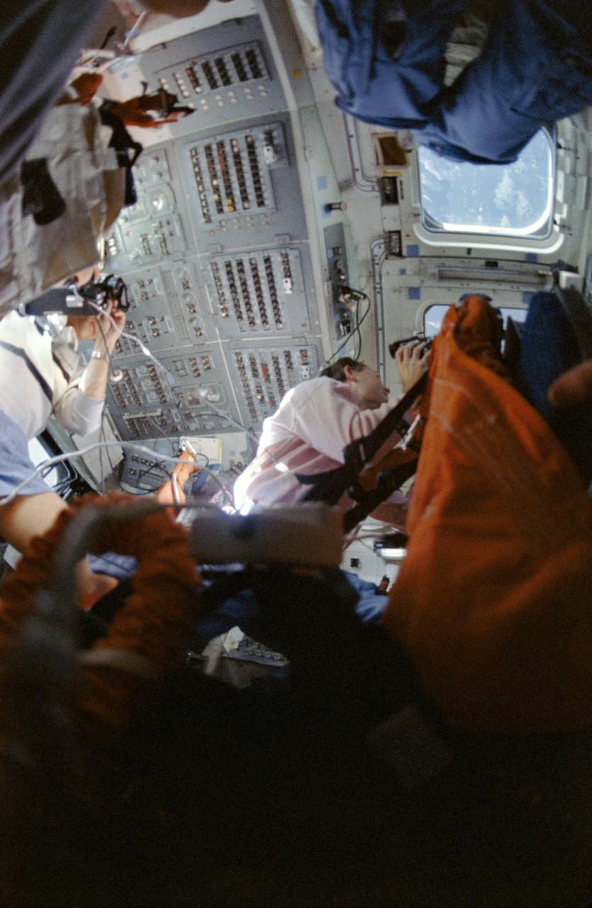 STS033-05-014A (22-27 Nov 1989) --- A low-angle view of STS-33's two astronaut medical doctors doubling as photographers and Earth observers on the flight deck of the Earth-orbiting Space Shuttle Discovery. Astronauts Story Musgrave, left, and Manley L. Carter and three other crewmembers shared five days aboard the Discovery for this DOD-devoted mission.