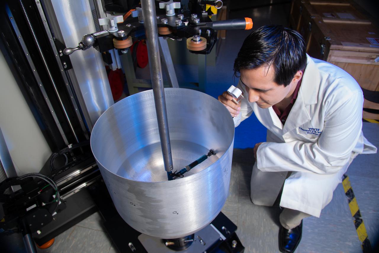 Edgar Reyes, a materials engineer and recent graduate of The University of Texas at El Paso, visually inspects a crack identified on the outer surface of a composite overwrapped pressure vessel (COPV) following an internal eddy-current through-wall nondestructive inspection conducted at the NASA White Sands Test Facility in Las Cruces, N.M.  Eddy-current testing is one of many electromagnetic testing methods used in nondestructive testing to identify cracks in COPVS that can potentially threaten spacecraft crew and mission success.   Photo Credit: (NASA/Reed P. Elliott)